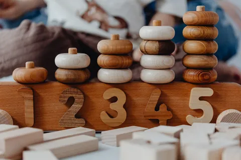 A wooden counting toy showing stacked rings above the numbers one through five
