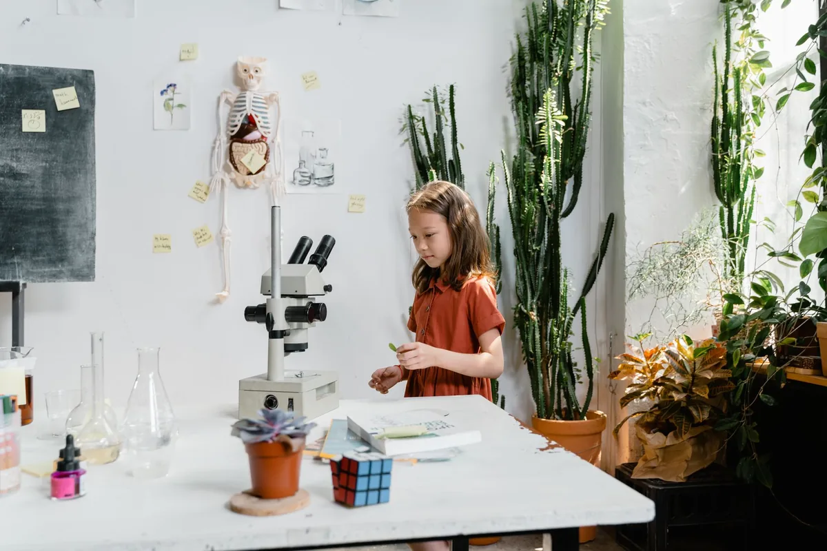A child examining samples at a science workbench surrounded by lab equipment and plants