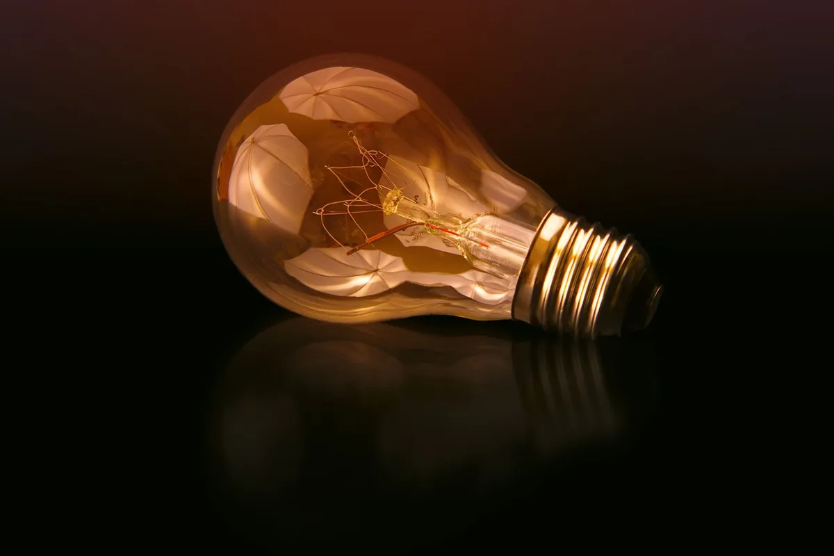 A glowing incandescent light bulb lit up against a dark background