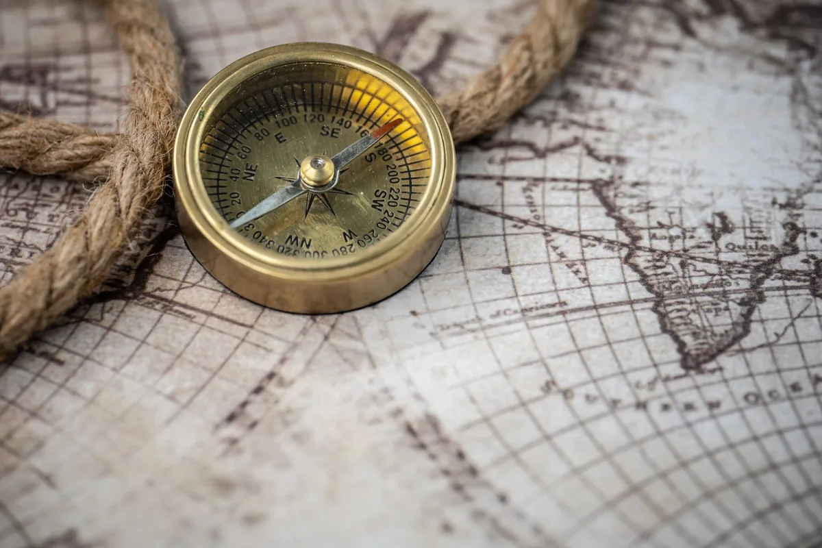 A brass compass resting on an old world map