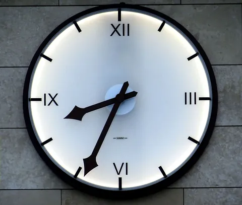 A wall clock with Roman numerals showing the hour and minute hands