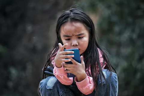A child looking closely at a smartphone screen