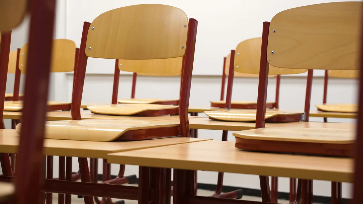 An empty classroom with wooden chairs stacked on desks