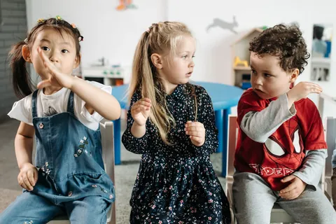 Three young children playing energetically in a kindergarten classroom