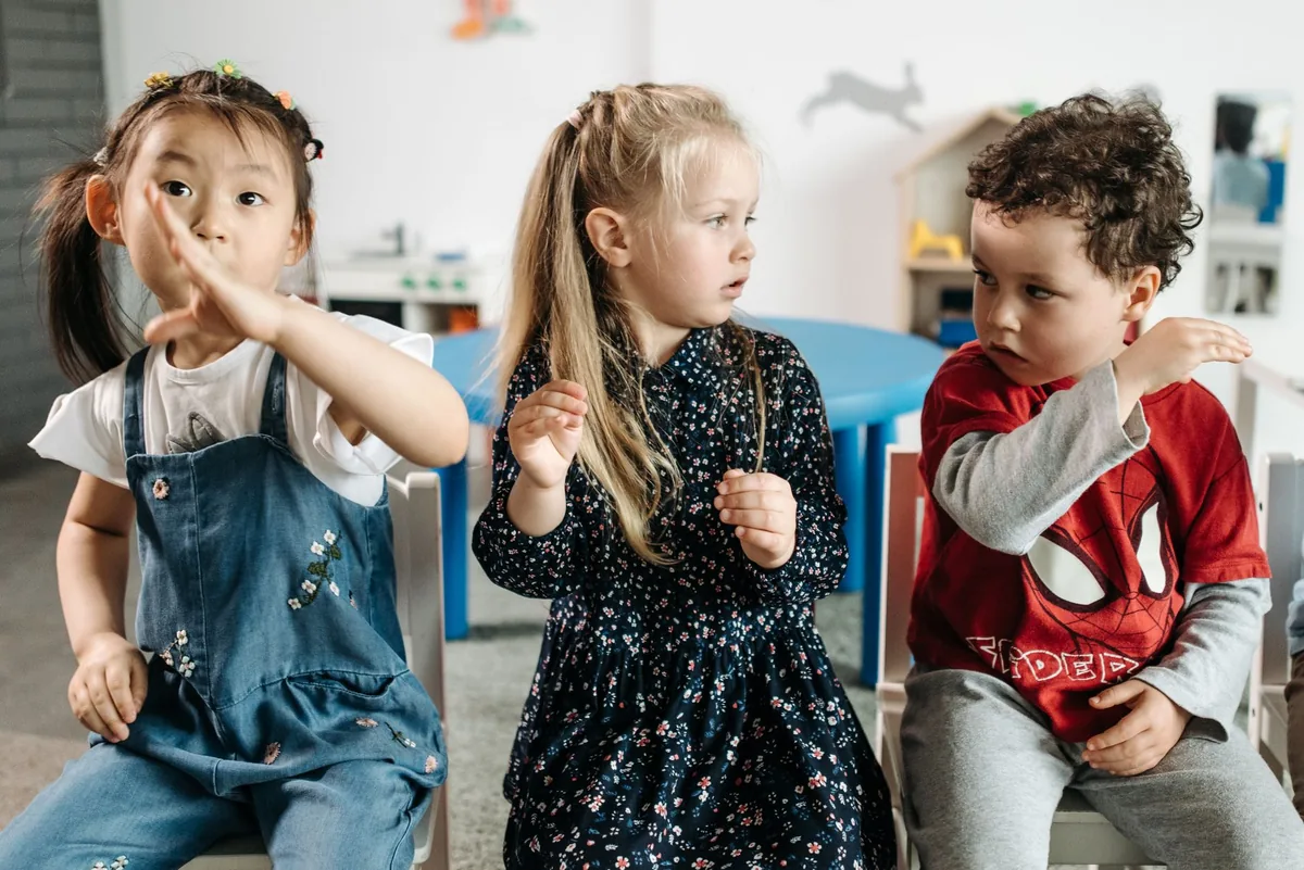 Three young children playing energetically in a kindergarten classroom