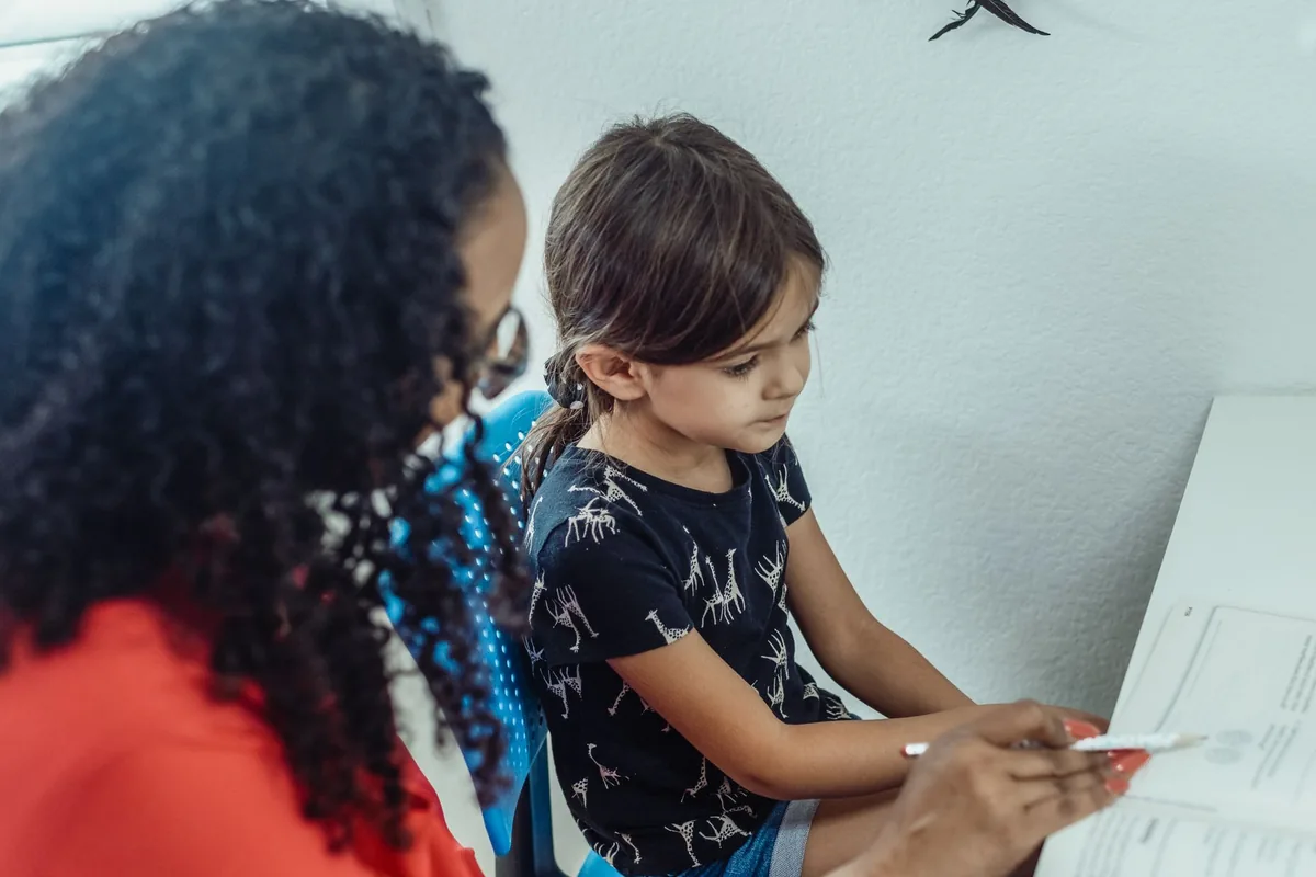 A tutor helping a young student one-on-one with a book