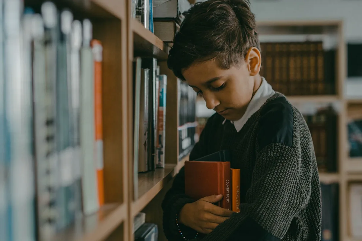 A child browsing books among tall library shelves