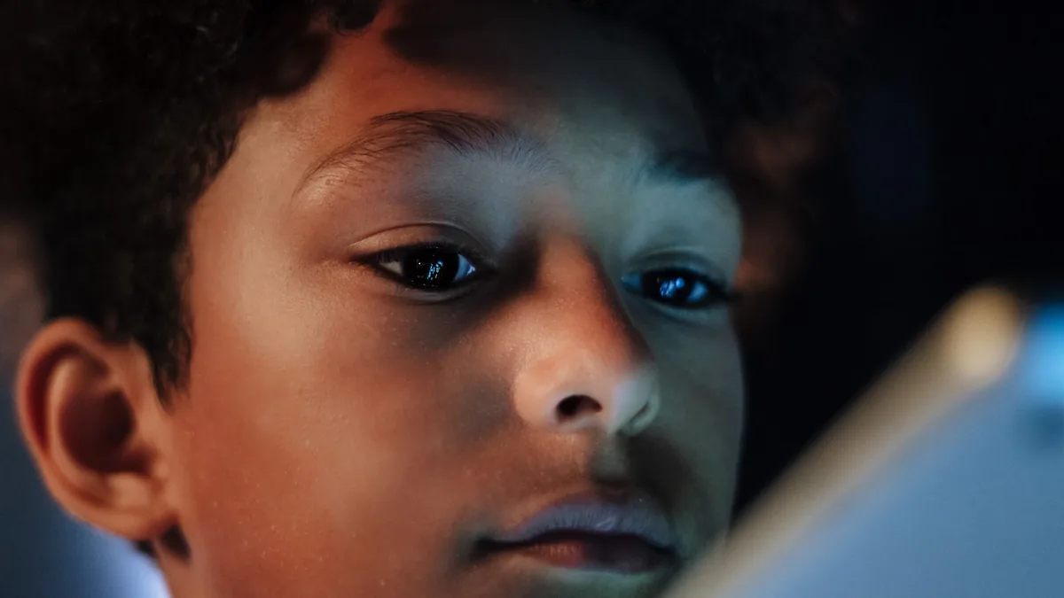 A child's face lit by the glow of a screen in a darkened room